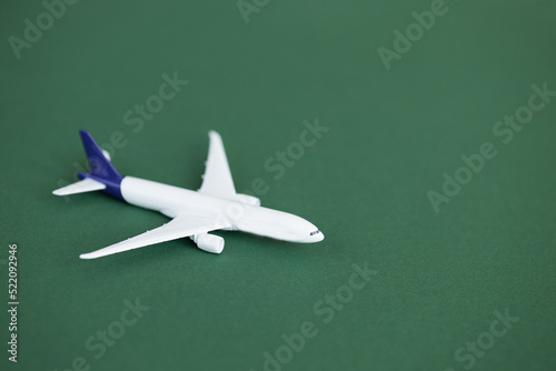 Miniature toy airplane on green background. Summer holiday air travel by plane concept. © ALEXSTUDIO
