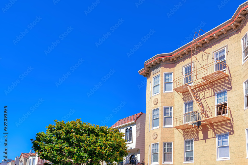 Aparment building with painted lined stucco wall and emergency ladder along with the suburbs houses Aparment building with painted lined stucco wall and emergency ladder along with the suburbs houses