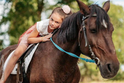 The girl lies on a horse and hugs her. Rehabilitation of a child through contact with a horse.