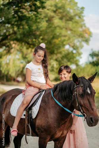 Walk mother with daughter and horse in the summer in the forest.