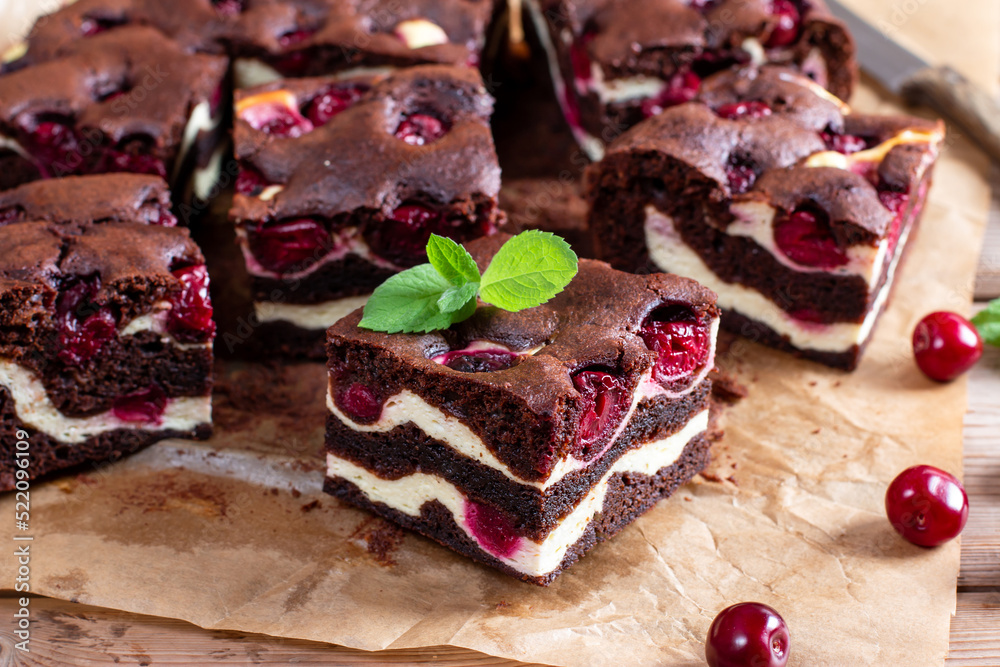 Chocolate brownie pieces decorated with cherry on wooden table