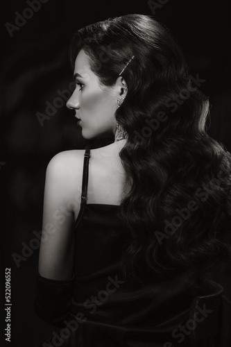 Portrait of elegant woman in vintage retro style of black and white Hollywood film with makeup and hairstyle. Brunette girl with jewelry in noir look photo