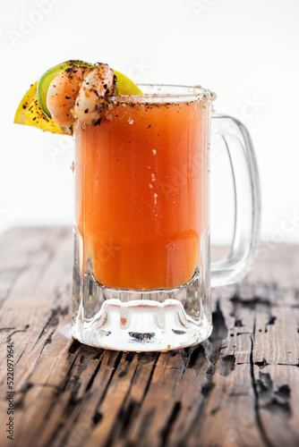 La michelada es una bebida alcohólica Mexicana que se prepara mezclando cerveza, jugo de limón, picante y sal, y agregando salsas sazonadoras photo