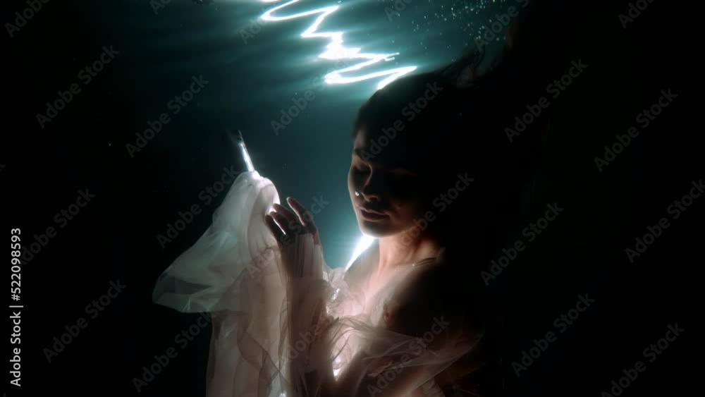 charmed lady is swimming inside sea water with glowing and, mysterious underwater portrait