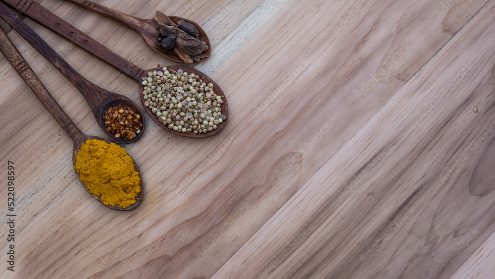 Top view of four old spoons with spices, herbs beans and cinnamon food wooden texture background arrangement.