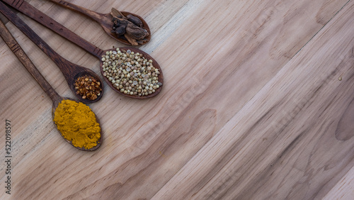 Top view of four old spoons with spices, herbs beans and cinnamon food wooden texture background arrangement.