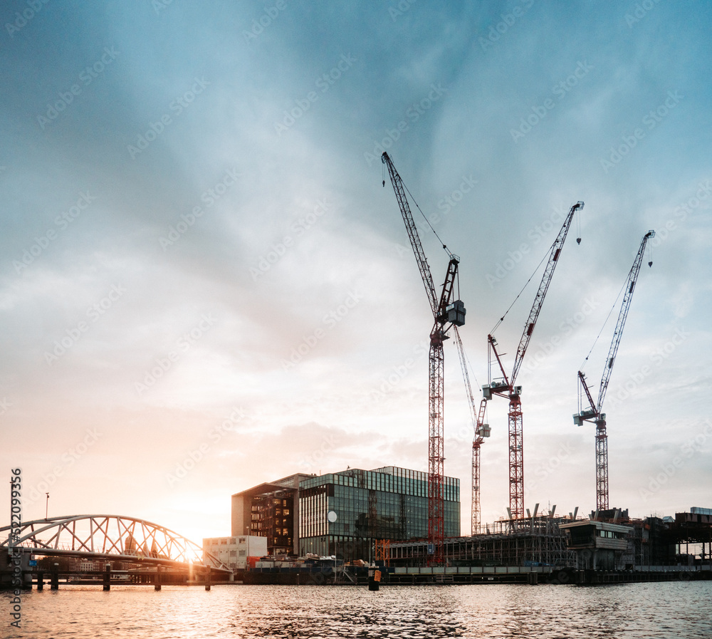 construction cranes in the evening light at the water construction cranes in the evening light at the water