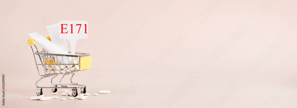 Titanium dioxide, E171, dangerous additive concept. gum, pills, toothpaste, cream in basket and sign with E171 on beige background. copy space banner