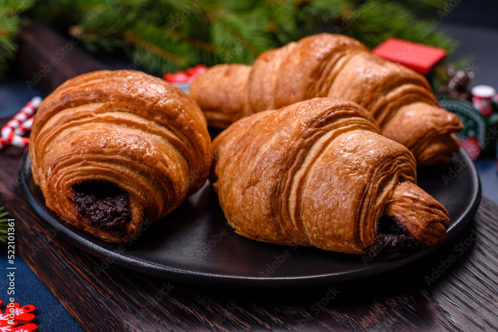 Crispy chocolate croissant with Christmas decorations on wooden cutting board Crispy chocolate croissant with Christmas decorations on wooden cutting board