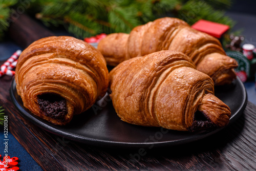 Crispy chocolate croissant with Christmas decorations on wooden cutting board
