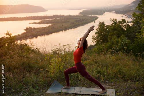 middle aged woman  praticing yoga at sunset on the mountain.  solo outdoor activities.  