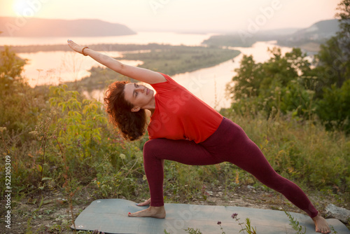middle aged woman  praticing yoga at sunset on the mountain.  solo outdoor activities. 
