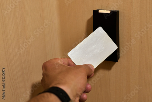 Hand approaching a card to an rfid reader to open a security door photo
