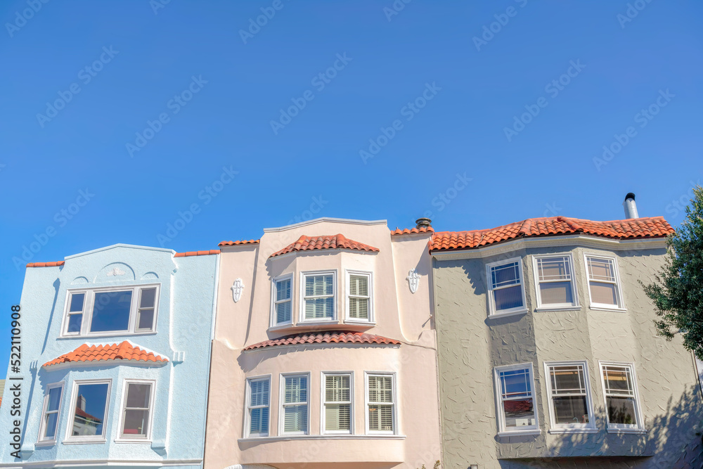 Three adjacent houses with clay roof tiles against the blue sky at San Francisco, California