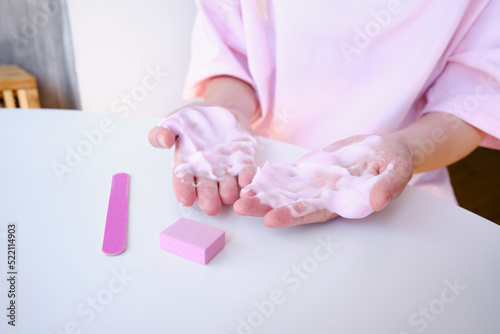 Manicure of female hands with soft soap or airy hand cream on a light background. Cosmetic care for hands and nails. Beauty and health