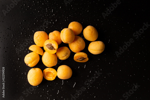 A handful of ripe raw apricots on a dark background