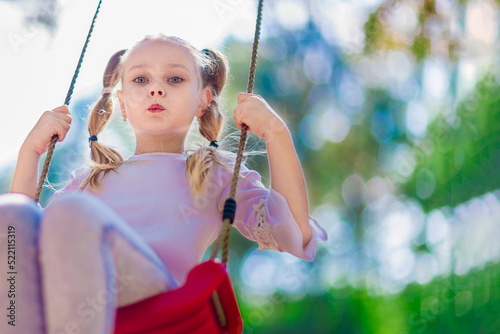 Little girl swinging on a swing outdoors in the forest
