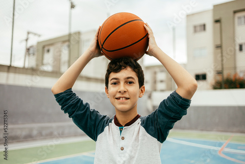 Portrait of 12 year old boy with basketball. Teenager training basketball outdoors. © kleberpicui