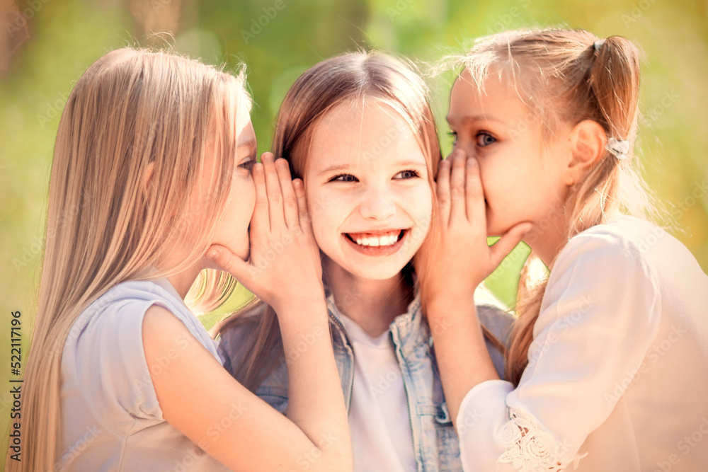 Naklejka premium Three cheerful young girls are whispering for a walk in the park