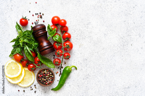 Pepper grinder, basil, cherry tomatoes on a white background with space for text. Food ingredients.