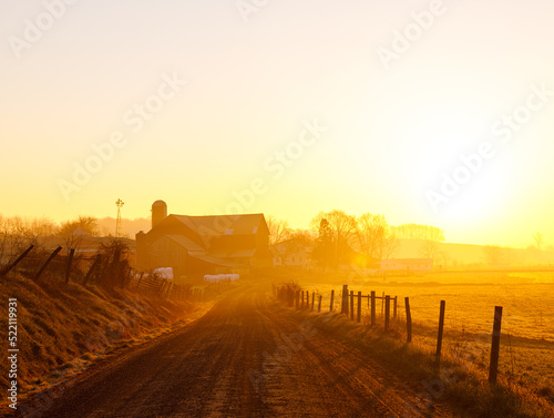 Country road leading to an Amish farm in the golden morning sunrise in Holmes County, Ohio