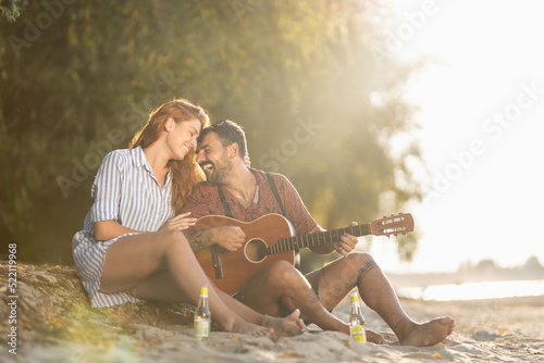 couple sitting on the beach, playing guitar © Nemanja
