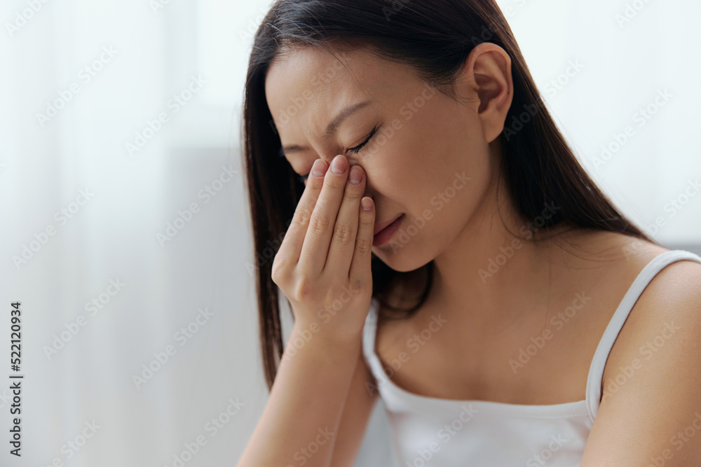 Rhinitis Sinusitis Flu. Suffering tormented tanned beautiful young Asian woman hold hand on nose bridge posing isolated on white background. Injuries Poor health Illness concept. Cool offer Rhinitis Sinusitis Flu. Suffering tormented tanned beautiful young Asian woman hold hand on nose bridge posing isolated on white background. Injuries Poor health Illness concept. Cool offer