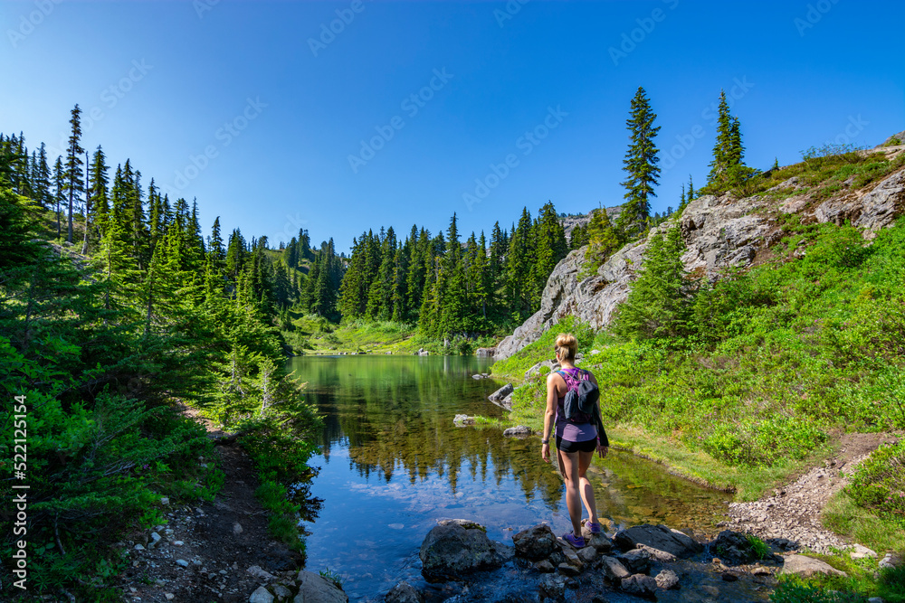 Adventurous athletic woman standing on the shore of an alpine lake in the Pacific Northwest. Adventurous athletic woman standing on the shore of an alpine lake in the Pacific Northwest.
