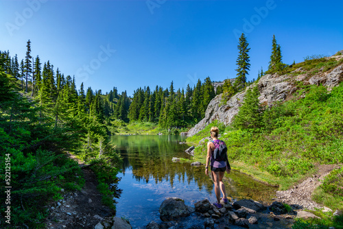 Adventurous athletic woman standing on the shore of an alpine lake in the Pacific Northwest.
