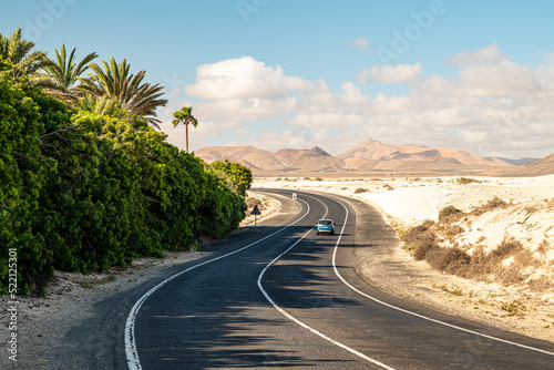 Blaues Auto auf der FV-104 in den Dünen von Corralejo mit Palmen auf Fuerteventura photo