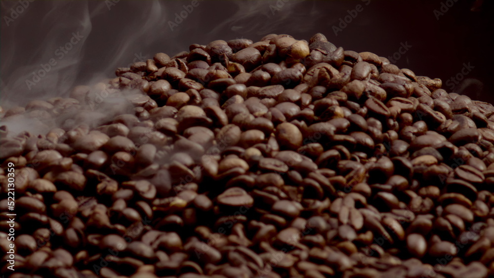Fototapeta premium Closeup steam rising over coffee seeds in slow motion. Roasting caffeine grains.