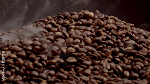 Closeup steam rising over coffee seeds in slow motion. Roasting caffeine grains.