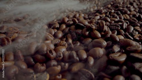 Steam coming coffee beans close up. Aromatic seeds roasting in super slow motion