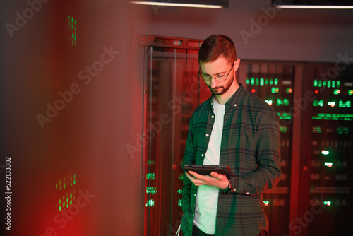 IT worker comparing settings with tablet while repairing software 