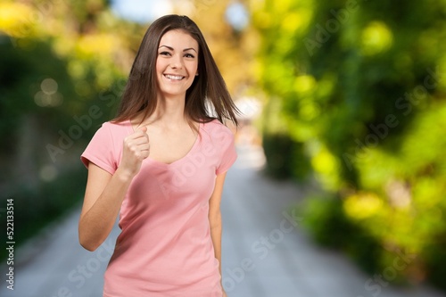 Fototapeta Naklejka Na Ścianę i Meble -  Smiling young woman in sportswear jogging at park on sunny day.