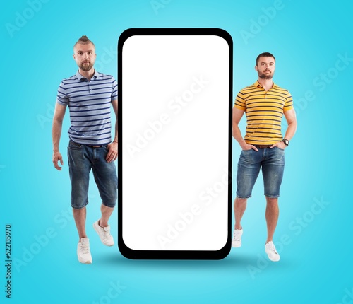 Happy young men stand near big mobile cell phone with blank screen