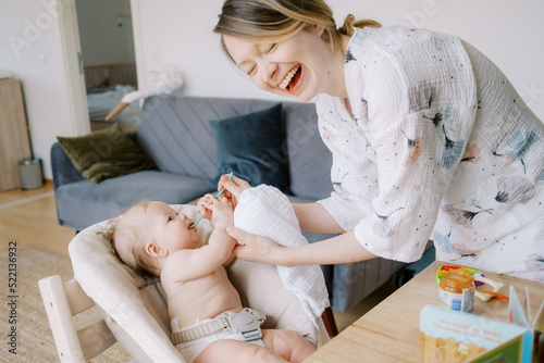 Laughing Mother Feeding Her Baby With Spoon photo
