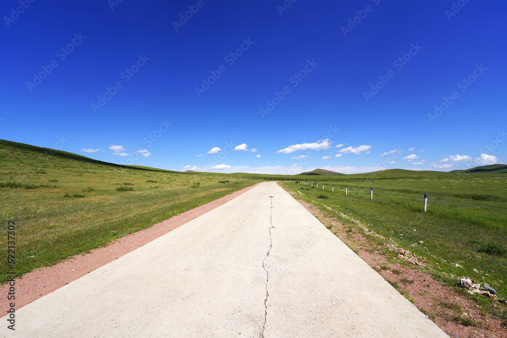 The tarmac road is under blue sky and white clouds