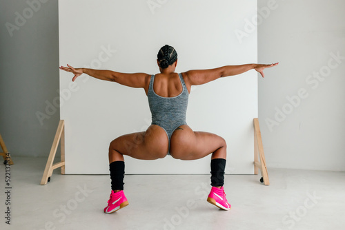 Back of squatting woman in thong bodysuit