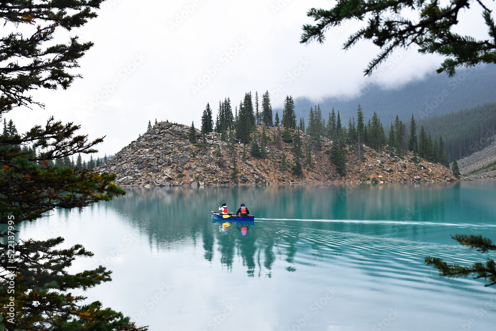 Two people in canoe in front of Rockpile trail on Moraine Lake in Banff