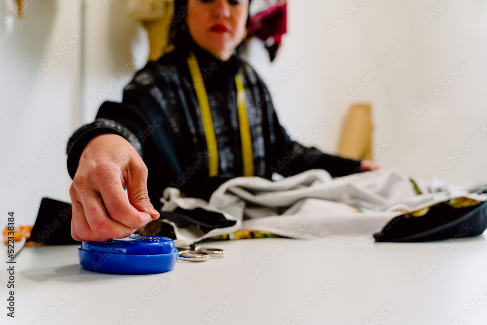 Dressmaker woman picking up needles to design clothes