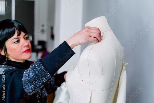 Obraz na płótnie Dressmaker woman trying on the mannequin her designed clothes. w salonie