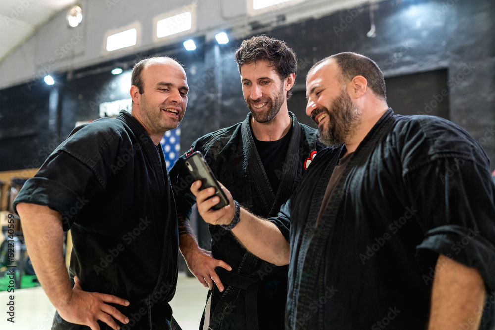 Happy martial artists watching video on smartphone Happy martial artists watching video on smartphone