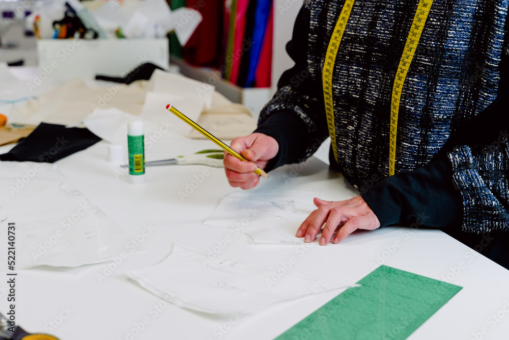 woman designing the clothes she creates in her workshop with pencil and paper.