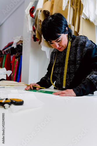 Dressmaker woman measuring the garments to design them.