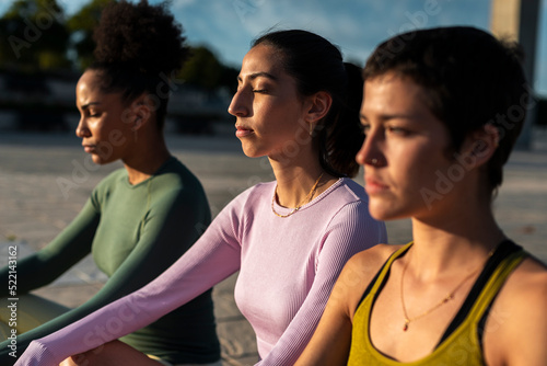 Diverse women meditating outdoors