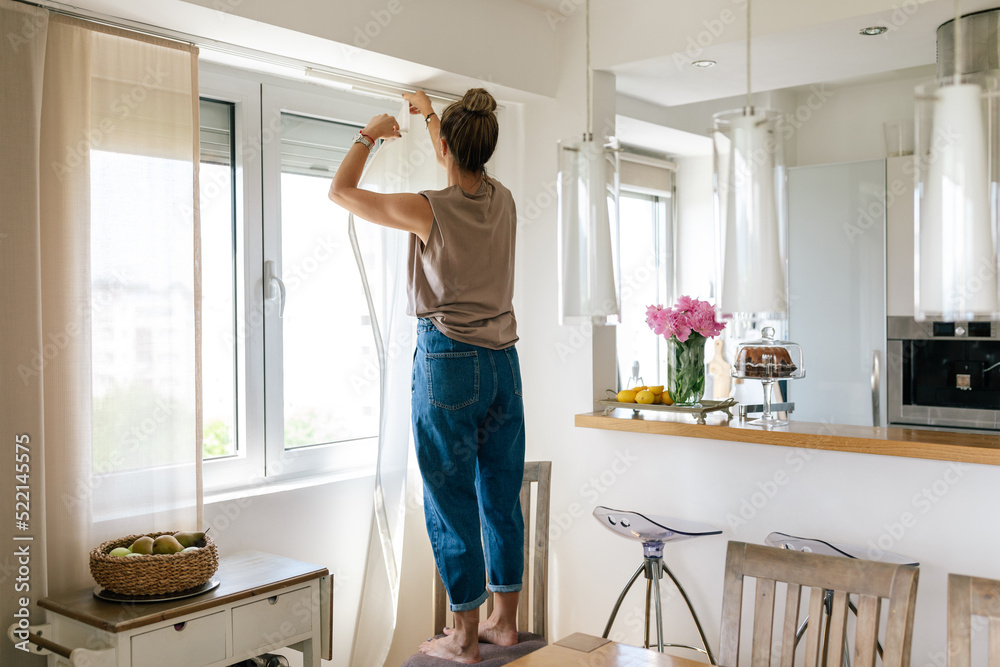 Woman Hanging Curtains At Home Woman Hanging Curtains At Home