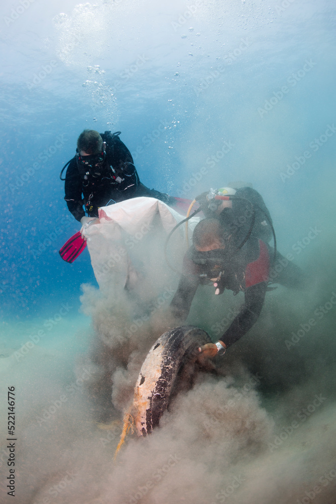 Scuba Divers Pulling Tire Trash Out of the Sea Scuba Divers Pulling Tire Trash Out of the Sea