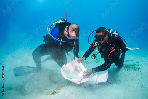 Diverse Buddy Team Scuba Diving Cleaning up the Ocean Floor photo