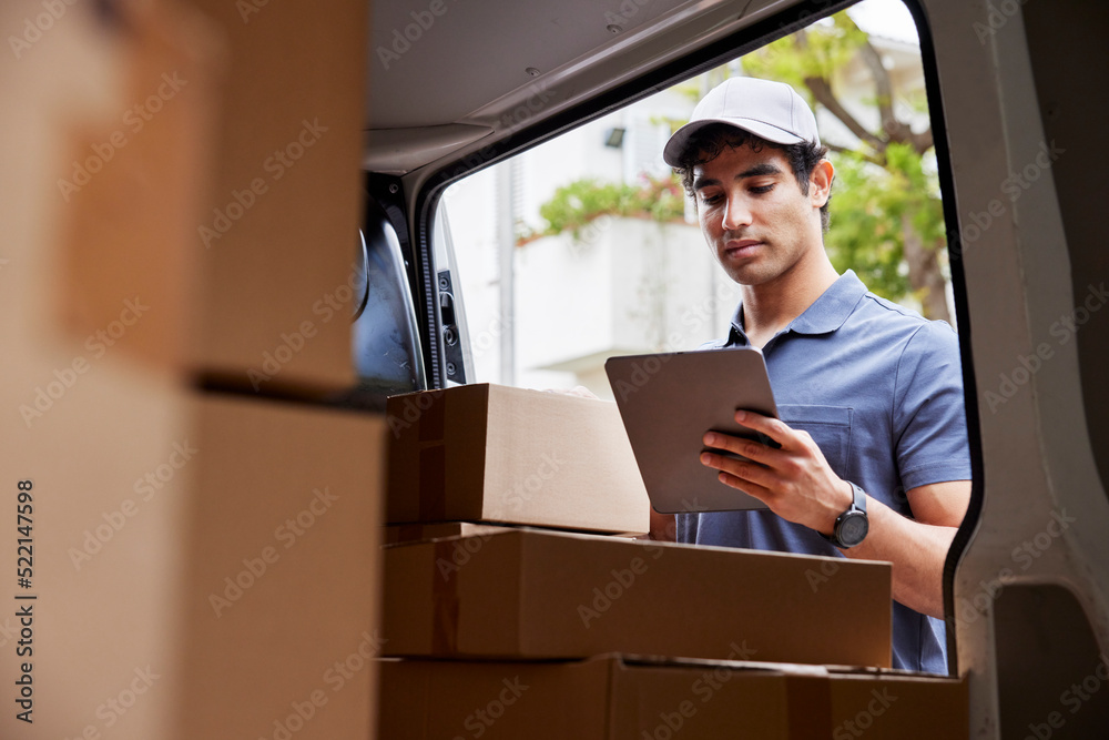 Male courier reading data on tablet near van Male courier reading data on tablet near van